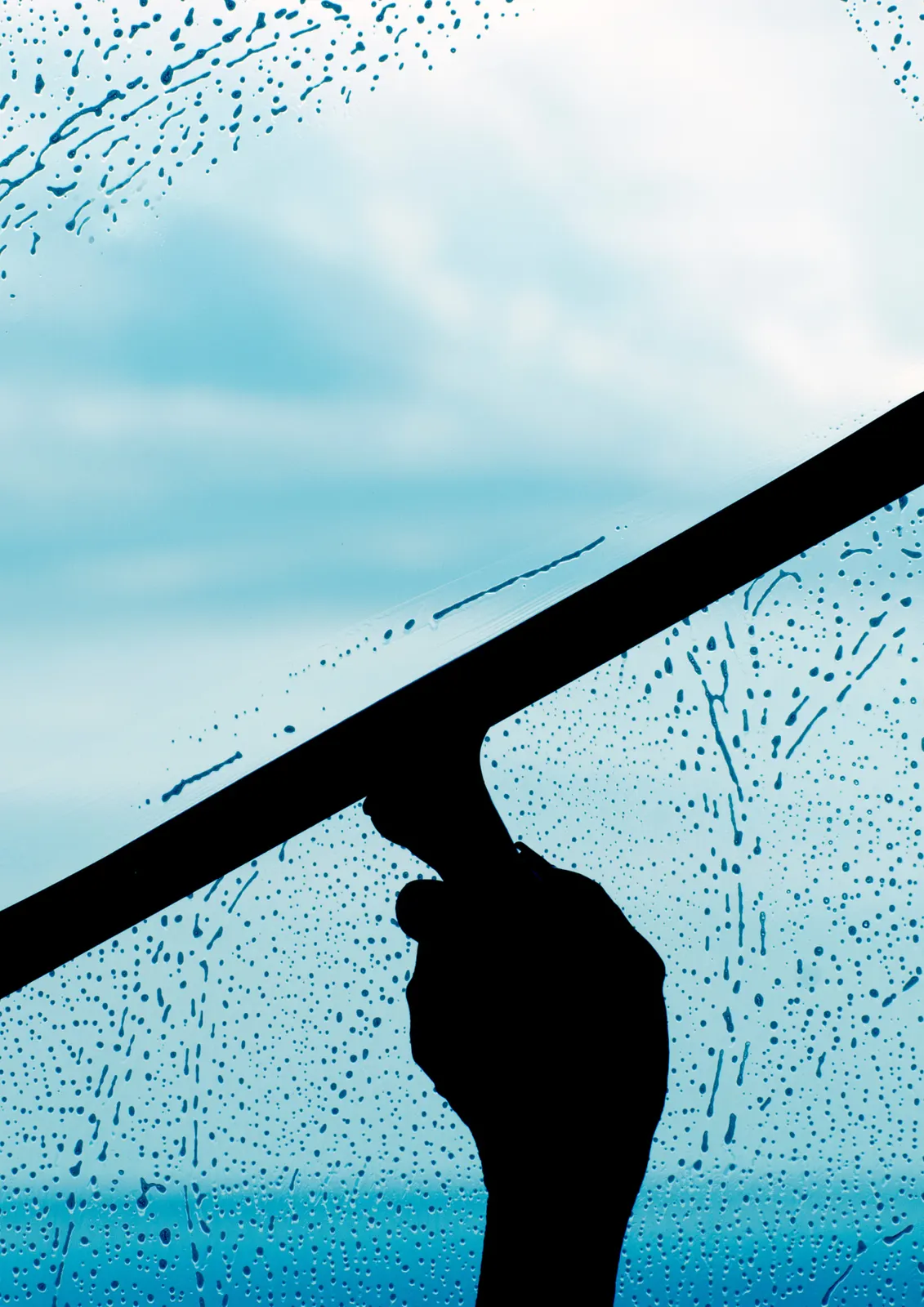Fensterreinigung mit dem Abzieher vor blauem Himmel